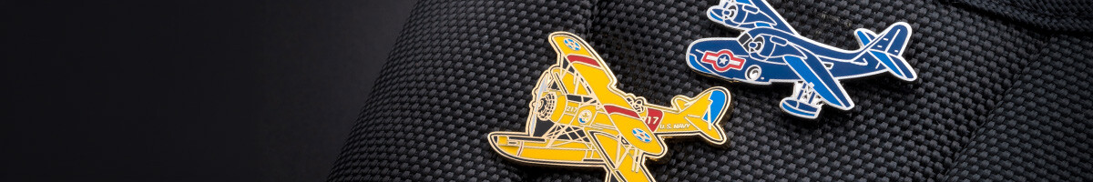 Blue and yellow U.S. Navy vintage aircraft cloisonné pins on a black ballistic nylon bag