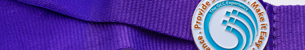 Blue and white GCC Experience logo pin attached to a purple conference lanyard