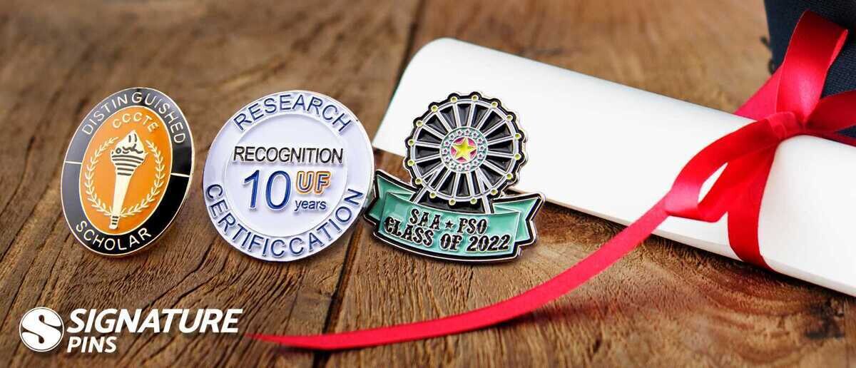 Three graduation pins beside a diploma: a Distinguished Scholar pin with torch, a UF 10 Years Research Recognition pin, and a SAA FSO Class of 2022 ferris wheel pin