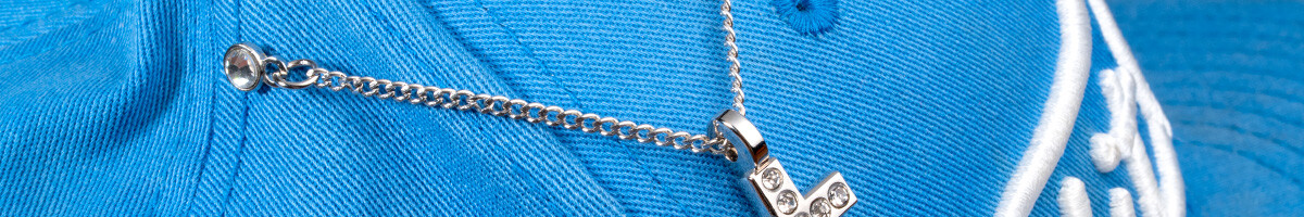 Silver cross pendant hat pin hanging from a chain across the crown of a blue cap