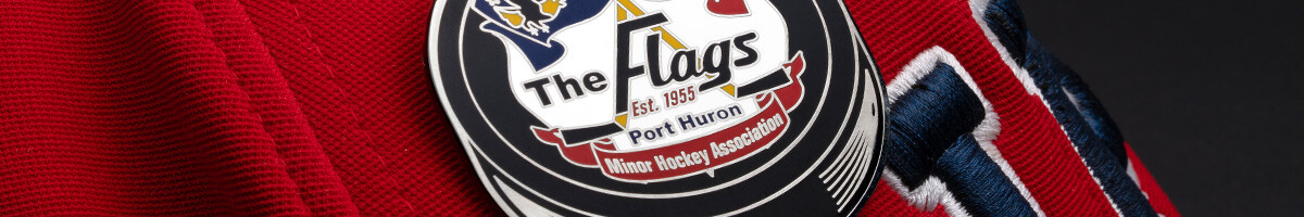 Close-up of a Port Huron Flags Minor Hockey Association puck-shaped pin on a red cap