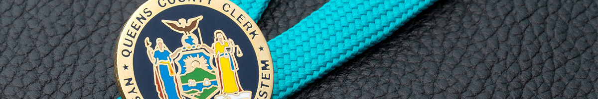 Queens County Clerk NYS Unified Court System seal pin in gold and navy on a teal lanyard