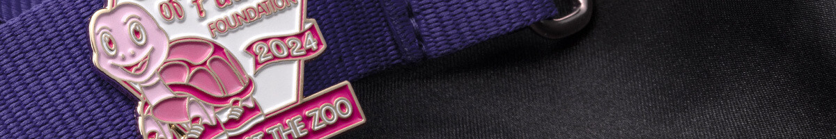 Pink and white Shades of Pink Foundation turtle pin clipped to a purple event lanyard