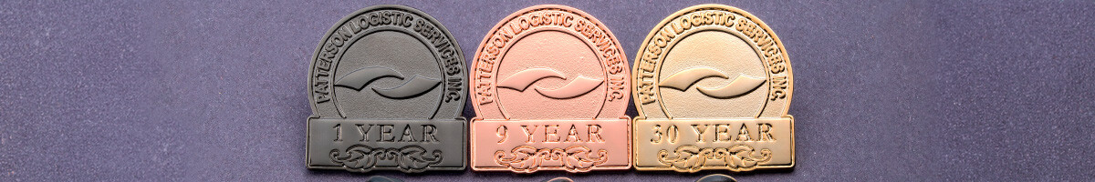 Three Patterson Logistic Services years of service pins in gunmetal, copper, and gold for 1 year, 9 years, and 30 years